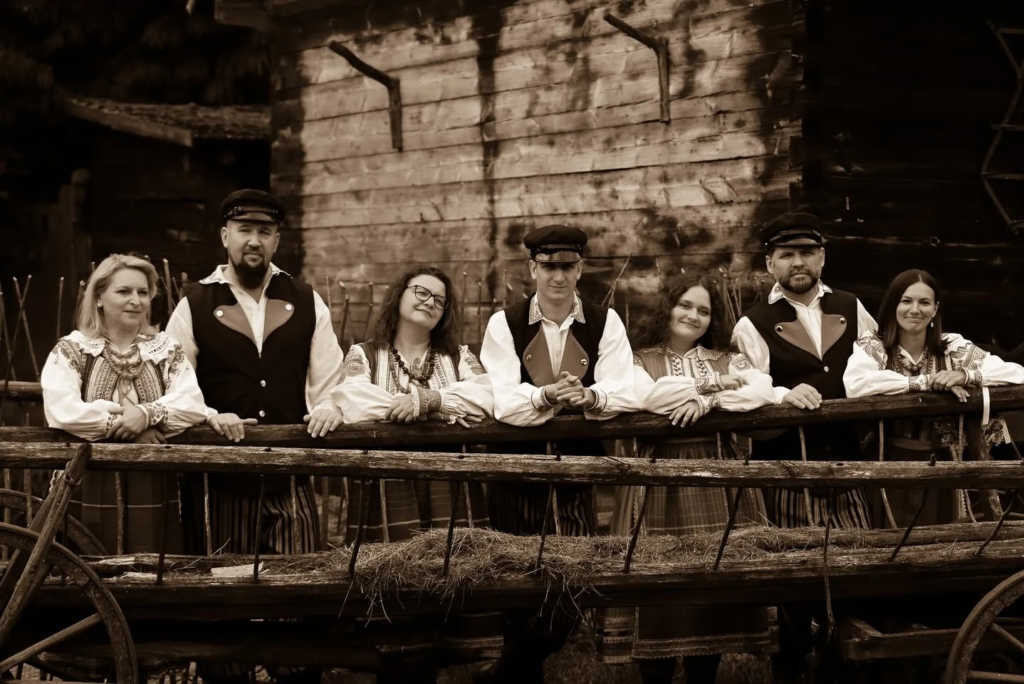 Uczestnicy sesji Barwy Folkloru przy drewnianej chacie